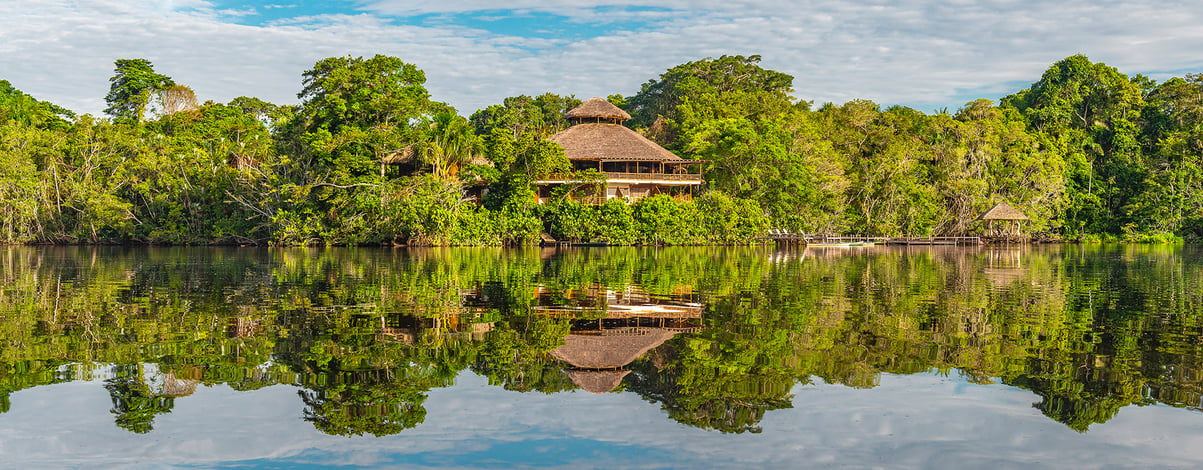 The reflection of an amazon rainforest lodge. The tributaries of the Amazon river comprise the countries of Suriname, Guyana, French Guyana, Venezuela, Colombia, Ecuador, Peru, Bolivia and Brazil